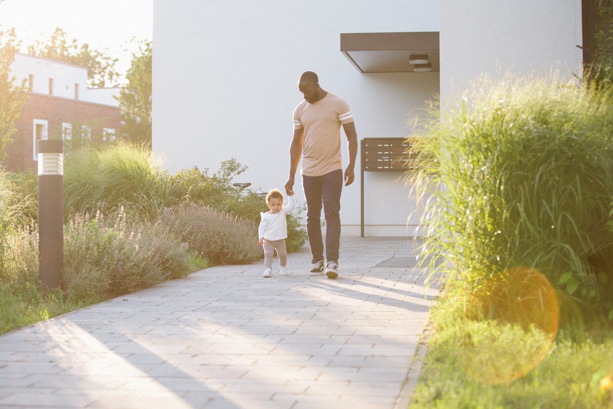 A man and child walking down the sidewalk.